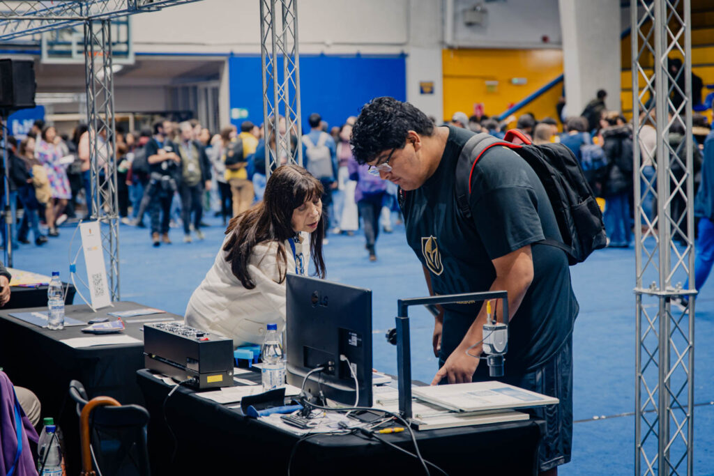 Stand de ARTIUC en la feria de bienvenida mechona, con estudiantes revisando los implementos guiados por equipo técnico de Artiuc.