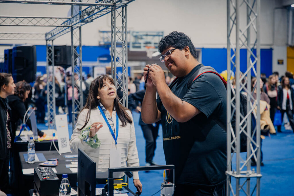 Stand de ARTIUC en la feria de bienvenida mechona, en la imagen un estudiante observa como se ve a través del telescopio.